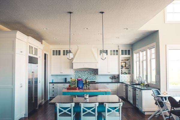 A kitchen fitted with a fridge, oven and cooker hood
