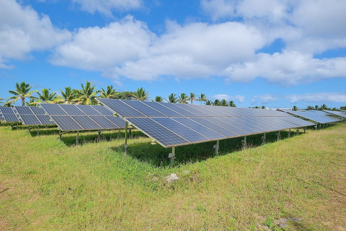 Rows of solar panels in a field under a blue sky