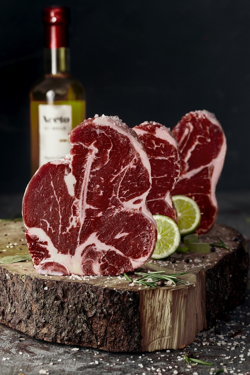 Raw T-bone steaks on a wooden board